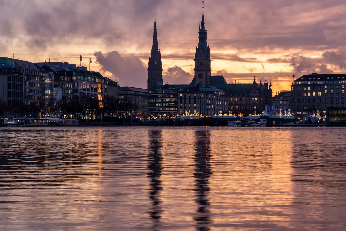 Die Binnenalster in der Abenddämmerung, dahinter die Türme von Rathaus und St. Nikolai.